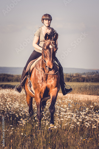 Mädchen galoppiert mit Pferd durch Blumen