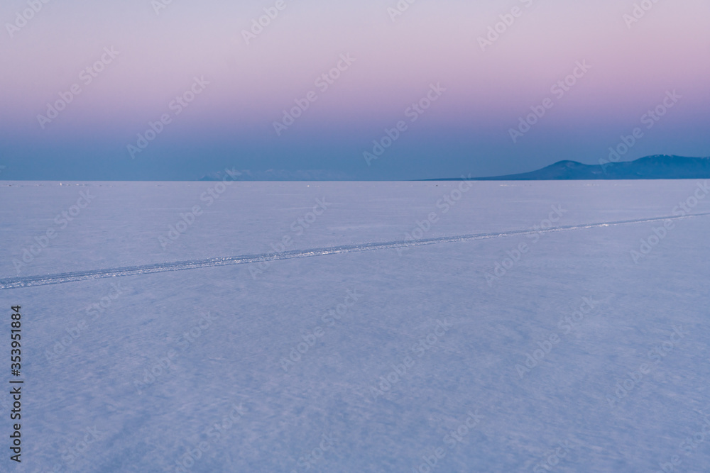 Snow-covered surface of Baikal Lake with track of bicycle. Siberia, Russia