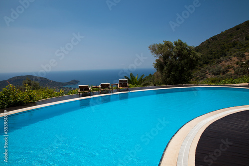 Swimming pool in the garden. Beautiful sea and mountain landscape.