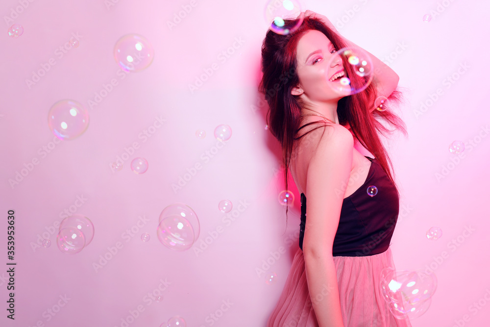 Beauty brunette girl with long hair. Model in a pink dress, flying dress, fabric. Pink makeup, style, fashion, beauty photo, soap bubbles, pink light Beauty brunette girl with long hair. Model in a pink dress, flying dress, fabric. Pink makeup, style, fashion, beauty photo, soap bubbles, pink light