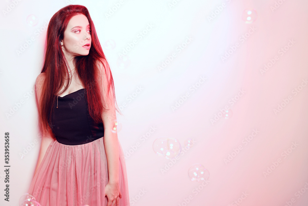 Beauty brunette girl with long hair. Model in a pink dress, flying dress, fabric. Pink makeup, style, fashion, beauty photo, soap bubbles, pink light Beauty brunette girl with long hair. Model in a pink dress, flying dress, fabric. Pink makeup, style, fashion, beauty photo, soap bubbles, pink light
