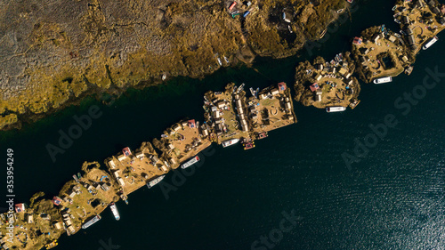 Aerial top view photo of floating islands next to each other on Lake Titicaca in Peru close to the big Totora plantation - the building material of each island. 