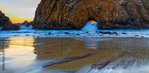 Fotografie Sunset Through Portal of Keyhole Arch aka Pfeiffer Beach Arch at Pfeiffer Beach,