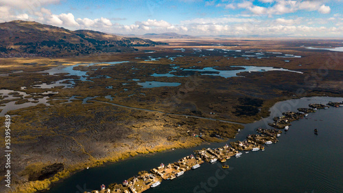 Aerial high view of Uros floating islands settlements at Lake Titicaca, Peru with hills, plantation of Totora and view of the coast in Puno. photo