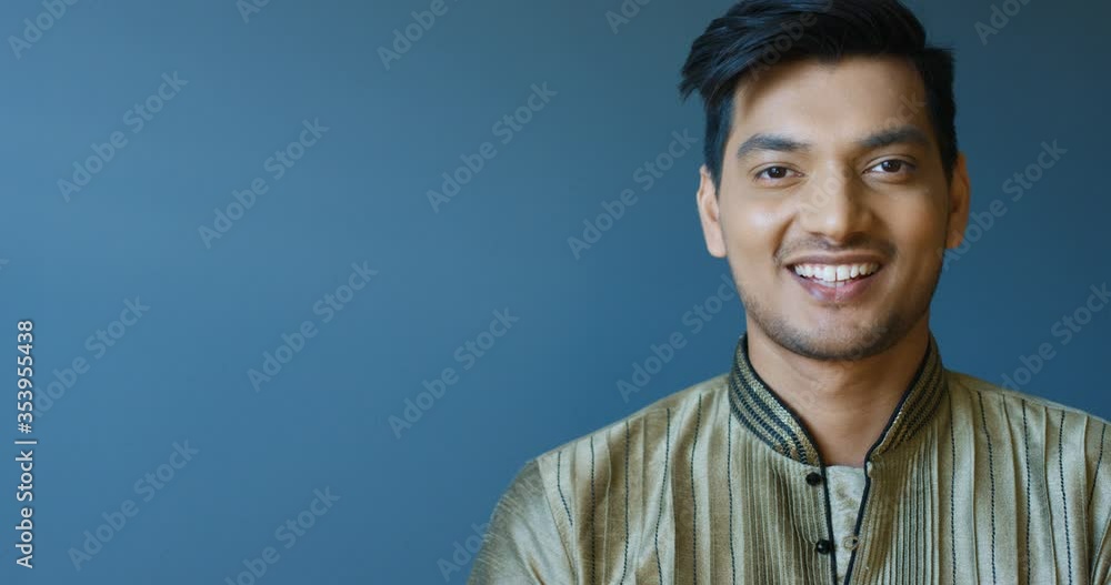 Portrait shot of handsome young Hindu cheerful man in traditional clothes smiling to camera. Close up of attractive happy guy laughing joyfully. Indoor. Portrait shot of handsome young Hindu cheerful man in traditional clothes smiling to camera. Close up of attractive happy guy laughing joyfully. Indoor.