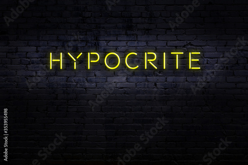 Night view of neon sign on brick wall with inscription hypocrite photo