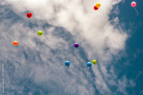 Several Colourful Baloons Flying Away on the Spring Blue Sky with the Clouds Background - Further