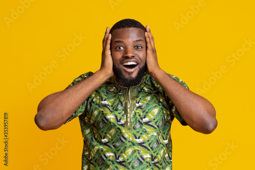 Amazed black man touching his head, yellow background