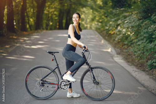 Woman with a bike. Sportswoman in a forest. Morning bike ride.