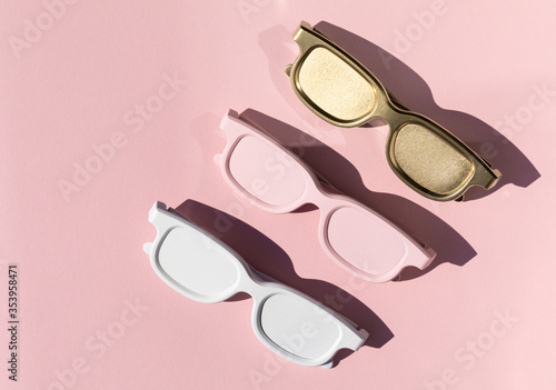 Colored sunglasses from the sun on a pink background. Creative concept.