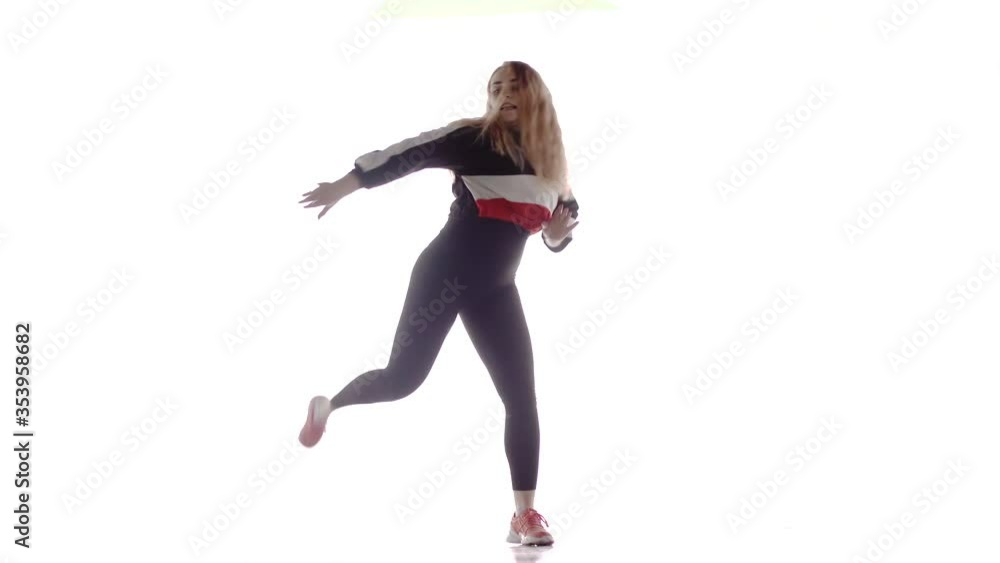 Attractive female modern style dancer performing in the studio. Hip hop street dance on a stage in front of the spotlight. Isolated. Contemporary choreography. Long shot Attractive female modern style dancer performing in the studio. Hip hop street dance on a stage in front of the spotlight. Isolated. Contemporary choreography. Long shot
