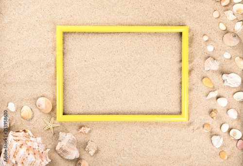 Yellow photo frame. Beach sand shells background.