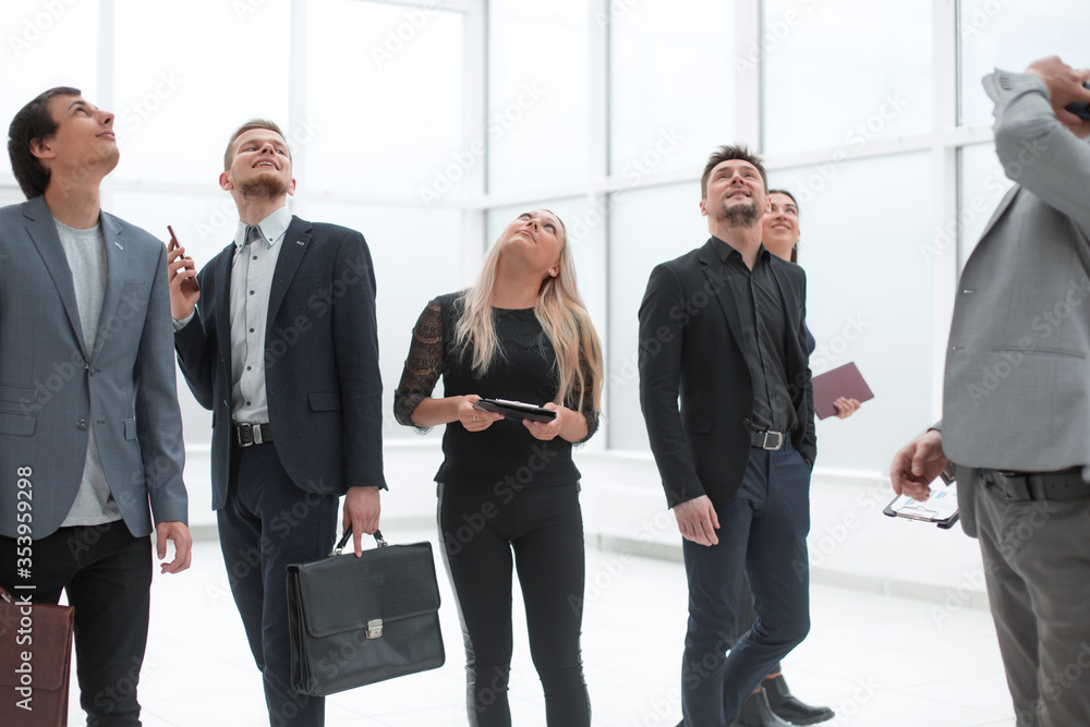 diverse employees standing in the office and looking somewhere up. diverse employees standing in the office and looking somewhere up.