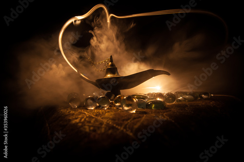 Lamp of wishes concept. Antique Aladdin arabian nights genie style oil lamp with soft light white smoke, Dark background. photo