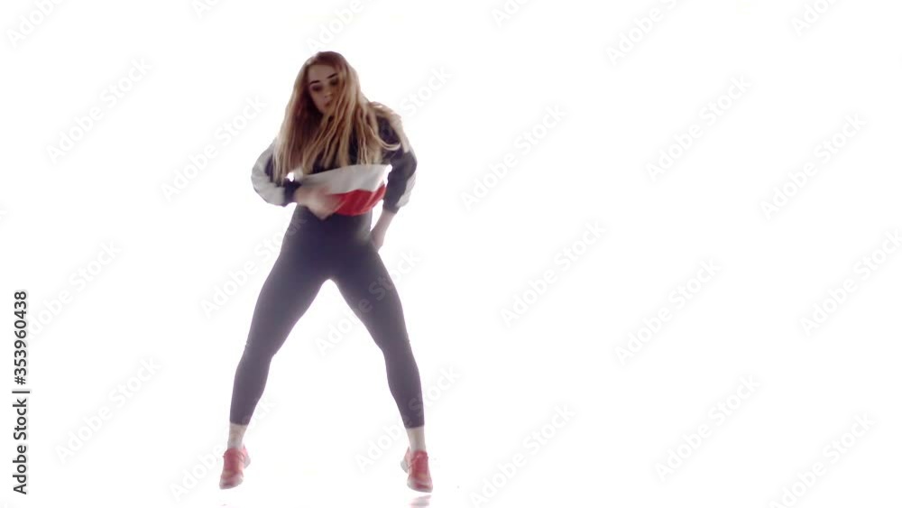 Attractive female modern style dancer performing in the studio. Hip hop street dance on a stage in front of the spotlight. Isolated. Contemporary choreography. Long shot Attractive female modern style dancer performing in the studio. Hip hop street dance on a stage in front of the spotlight. Isolated. Contemporary choreography. Long shot