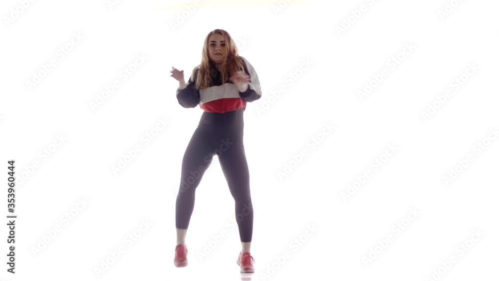 Attractive female modern style dancer performing in the studio. Hip hop street dance on a stage in front of the spotlight. Isolated. Contemporary choreography. Long shot Attractive female modern style dancer performing in the studio. Hip hop street dance on a stage in front of the spotlight. Isolated. Contemporary choreography. Long shot