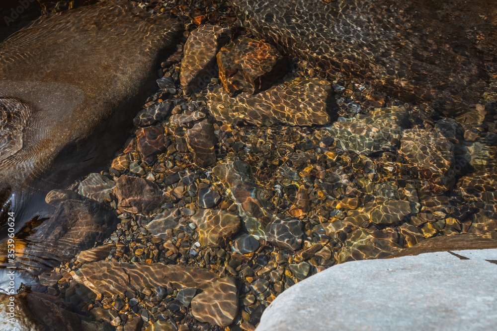 summer sunshine creates beautiful patterns on river stones under water summer sunshine creates beautiful patterns on river stones under water