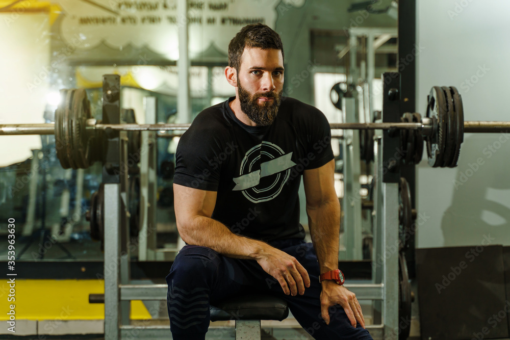 Front view portrait of young adult caucasian man in gym on the bench Front view portrait of young adult caucasian man in gym on the bench