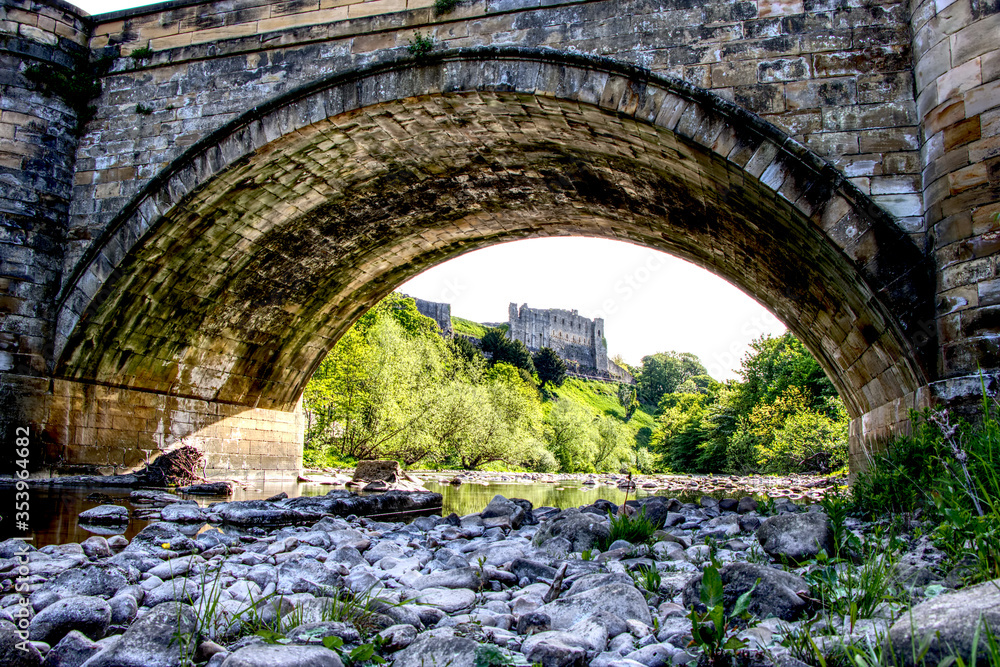 Looking under a stone bridge with Richmond castle in the background, North Yorkshire