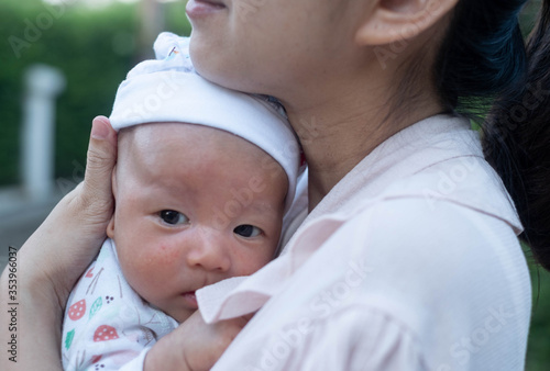 Portrait of a newborn baby infant hold close by mother in the garden, close up. Family,