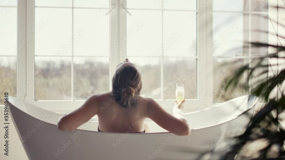 Cute girl sitting with a glass of champagne in the bathroom and resting Cute girl sitting with a glass of champagne in the bathroom and resting