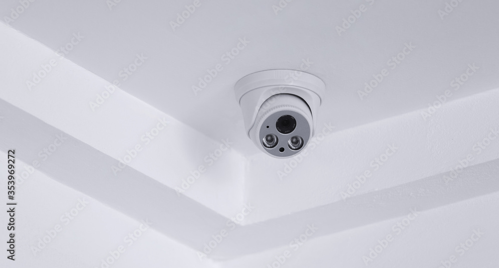 CCTV security camera on white ceiling, operating inside the building ...