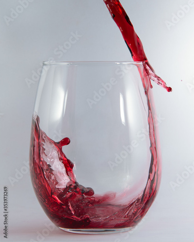 Red wine pouring and spilling over the edge of a stemless glass