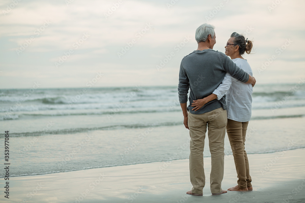 Rear view of Romantic senior couple standing together hugging each other on beach,.Retirement age concept and love, copy space for text,.image not focus