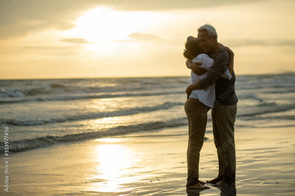 Romantic loving senior wife caress beloved husband cuddling and looking in eyes. on beach during sunset near sea,  Elderly love,.Retirement age concept and love, copy space for text
