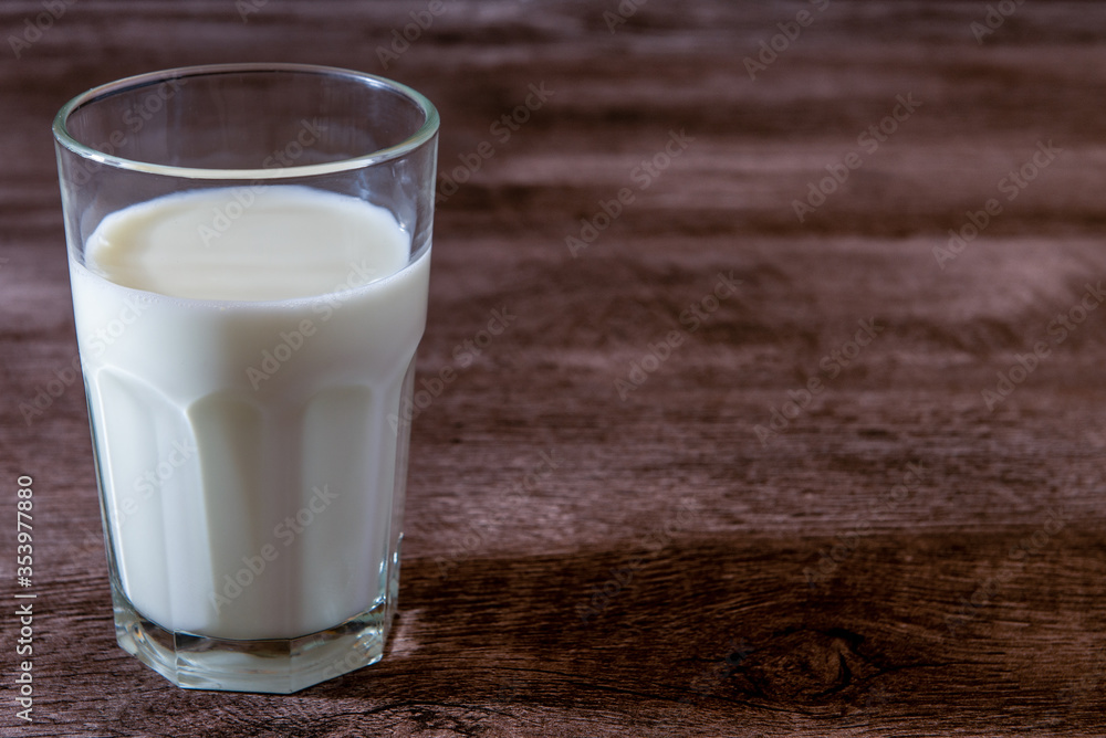 Leche en vaso de vidrio transparente sobre base de madera Leche en vaso de vidrio transparente sobre base de madera