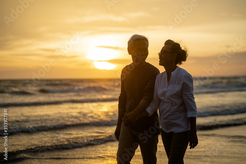 Happy Romantic of retired couple holding hands and walking together each other talking happily. Love is everything. evening light.. Retirement age concept and love, copy space for text