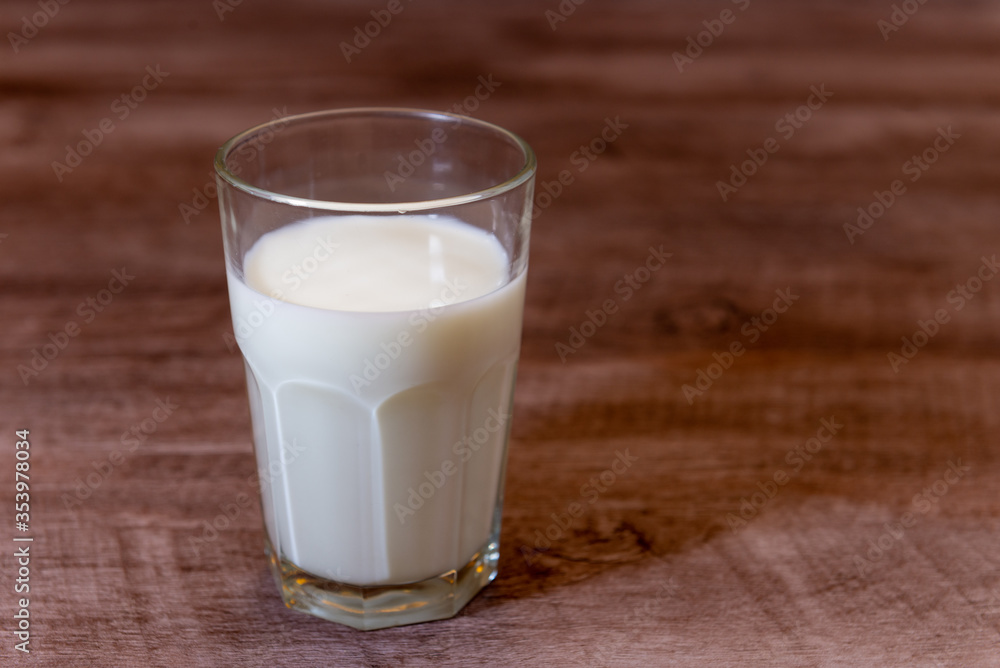 Leche en vaso de vidrio transparente sobre base de madera. Leche en vaso de vidrio transparente sobre base de madera.