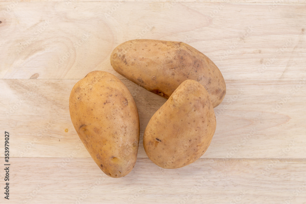 Three potatoes placed on a wooden background Three potatoes placed on a wooden background