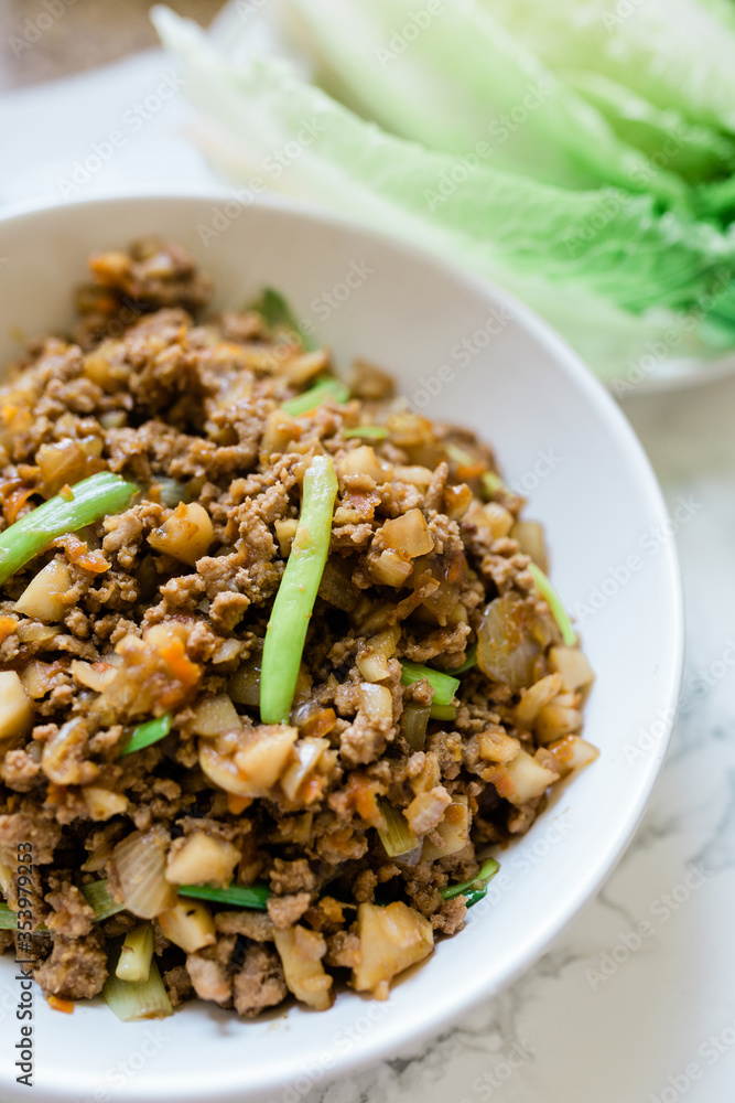 A Yummy Bowl of Stir-Fried Ground Chicken and Lettuce in the Background. 