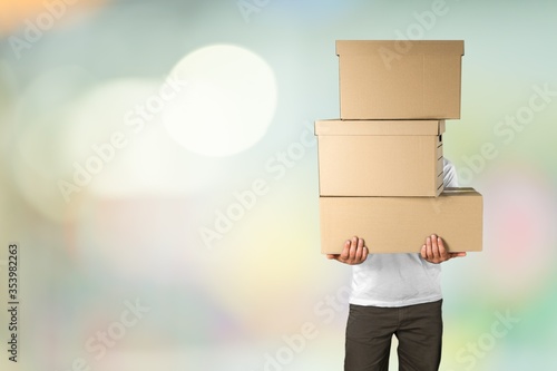 Delivery man carrying stacked cardboard boxes in front of face