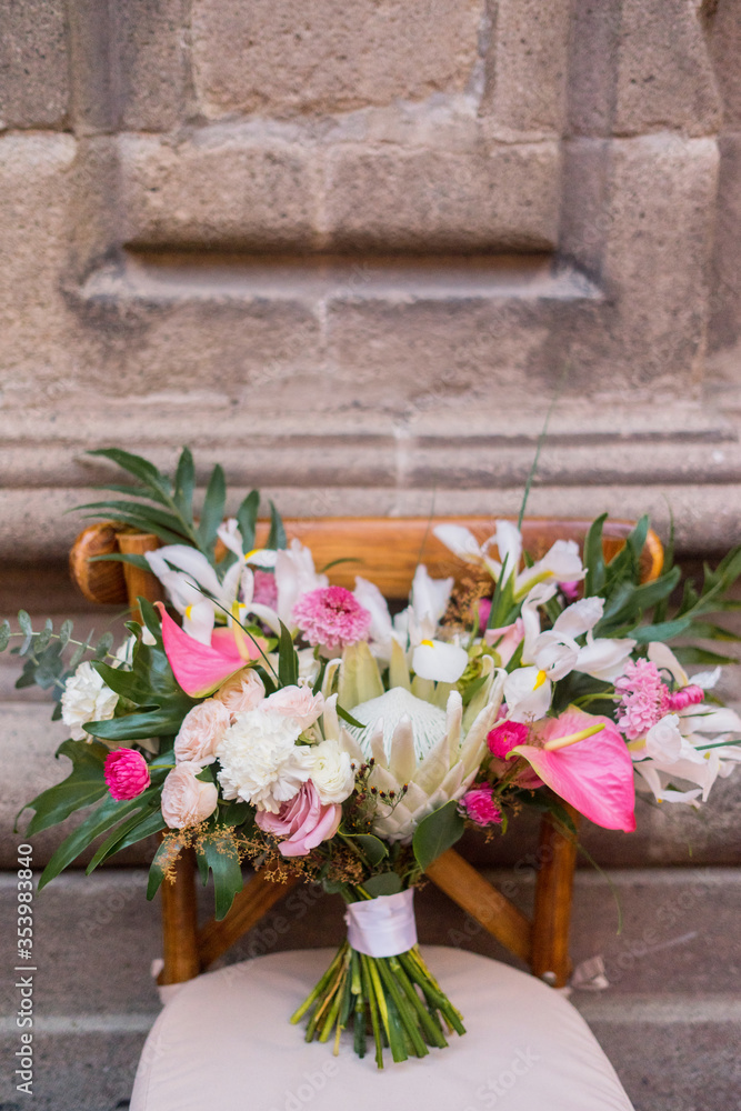 Bride bouquet with protea and anthurium on the wooden chair