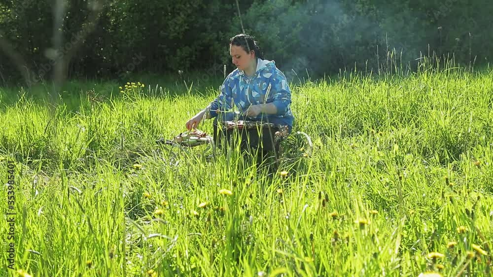 A woman on nature grills meat and sausages on the grill. A woman on nature grills meat and sausages on the grill.