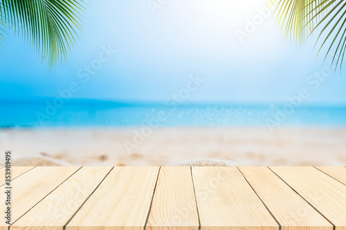 empty wooden table on the beach day light palm leaf.