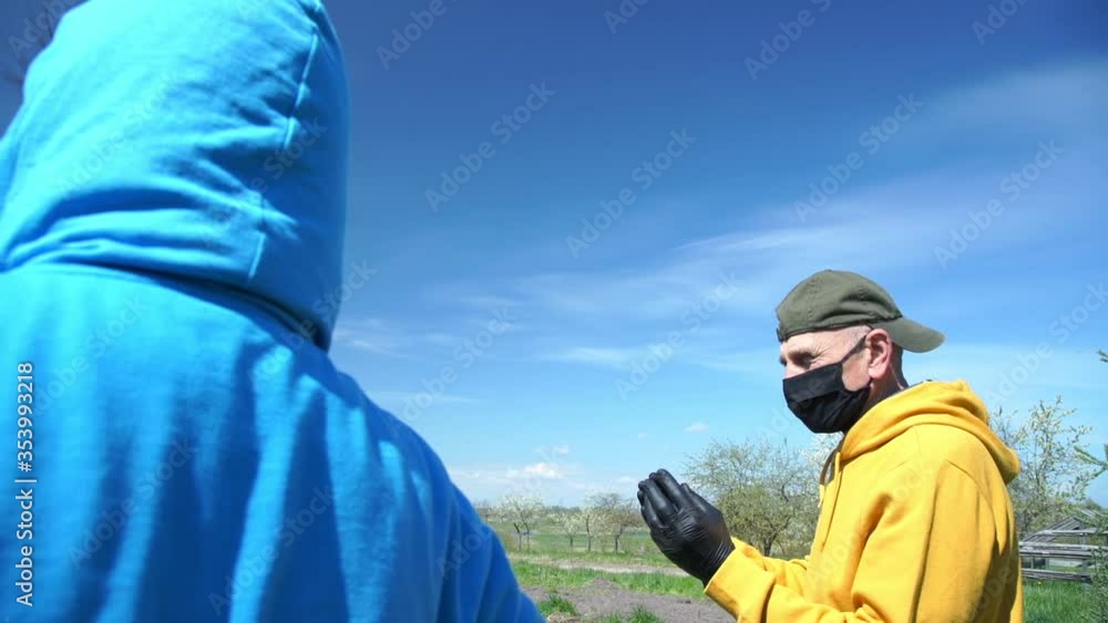 people in masks and jackets stand at distance discussing kitchen garden problems on sunny spring day slow motion side view