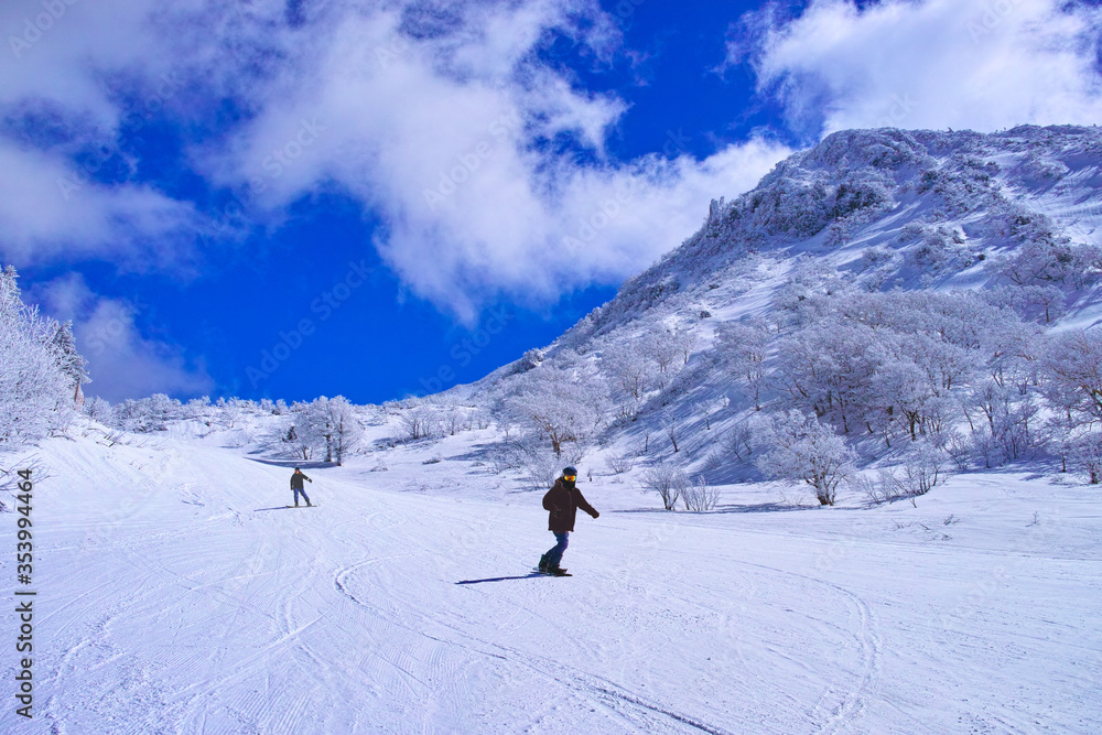 真冬のゲレンデを滑走するスノーボーダー達
