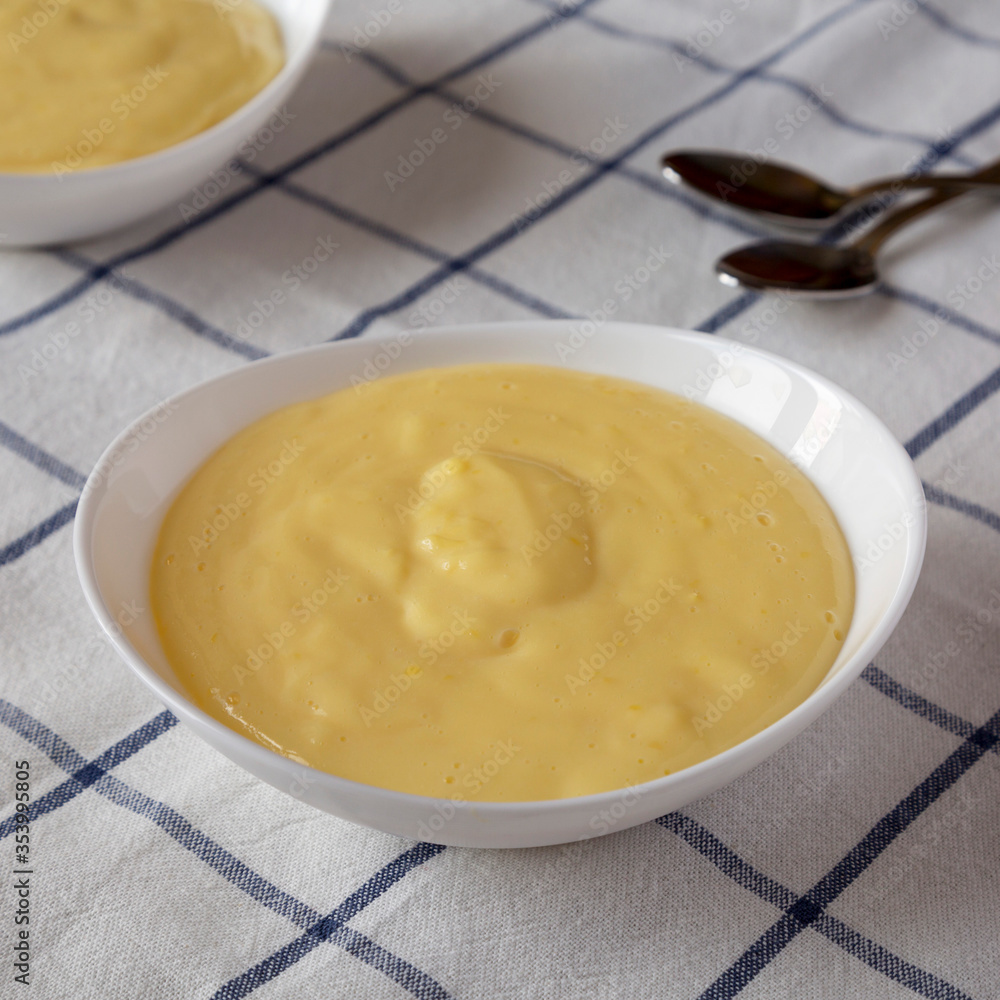 Homemade vanilla custard pudding in white bowls, low angle view. Close-up. Homemade vanilla custard pudding in white bowls, low angle view. Close-up.