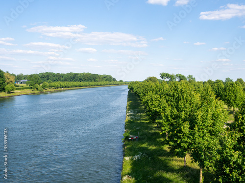 The Amsterdam-Rhine canal near a town called Houten, with trees on the banks. Sunny day. 