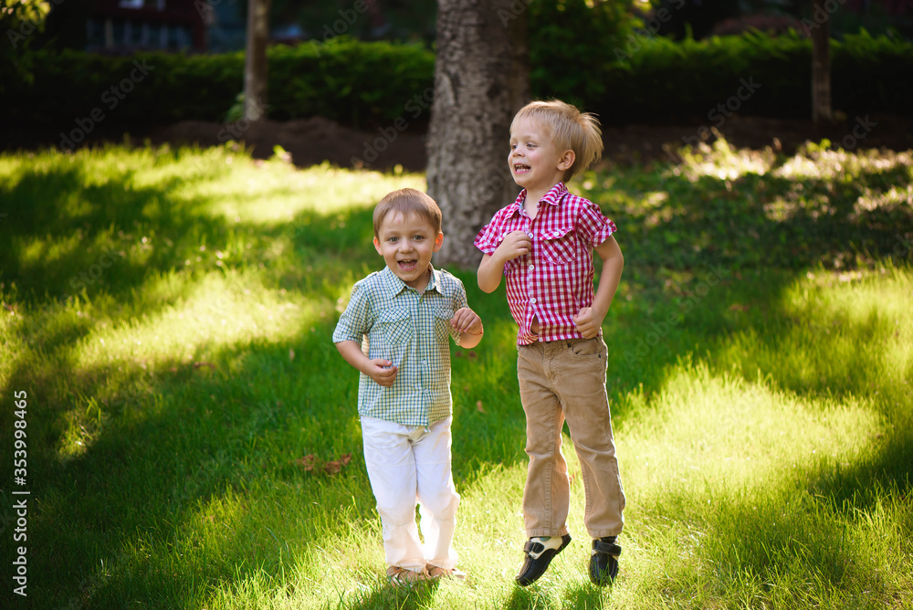 Fototapeta premium Two boys brothers playing and jumping outdoors in a park.