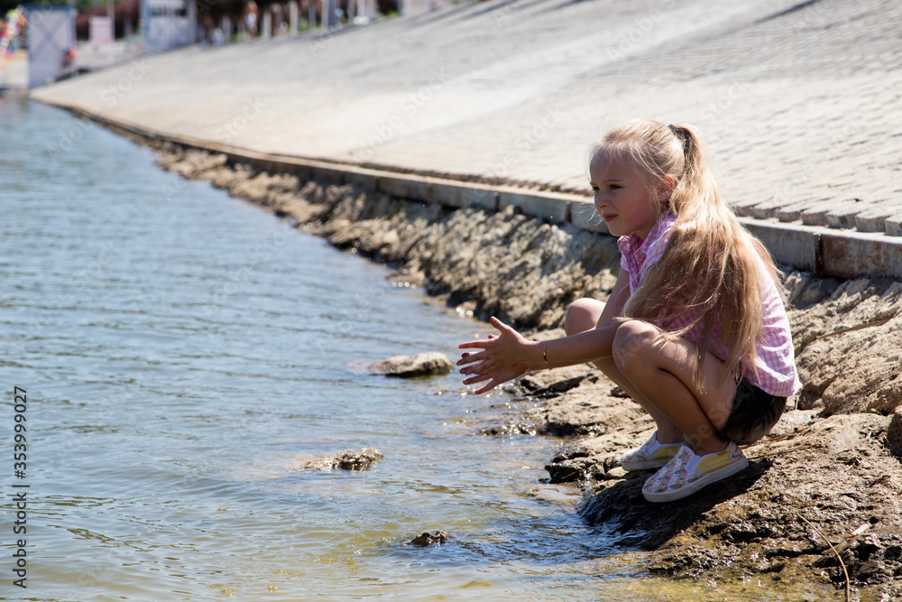 Adorable small girl sitting on the concrete dam. Stock Photo | Adobe Stock