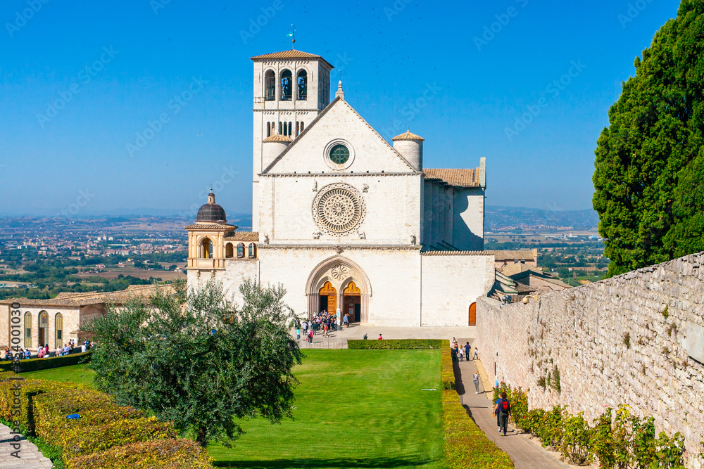 La Basilica di San Francesco ad Assisi, Umbria, Italia, con il prato antistante e il cielo blu sullo sfondo