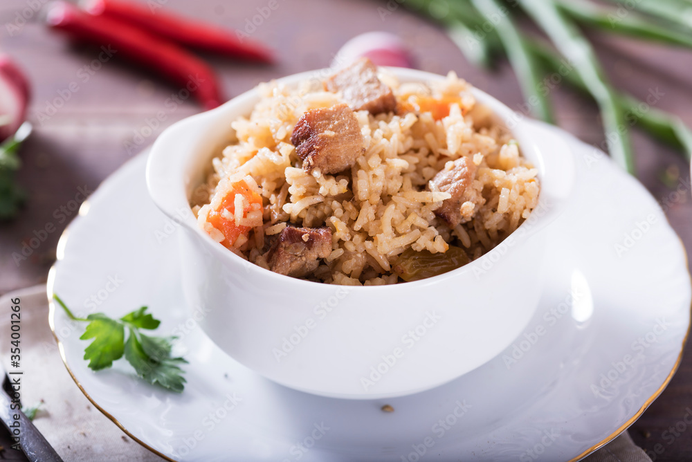 Pilaf - traditional Eastern dish made with rice, vegetables and meat. Asian food. The concept of oriental cuisine , on a wooden table Pilaf - traditional Eastern dish made with rice, vegetables and meat. Asian food. The concept of oriental cuisine , on a wooden table