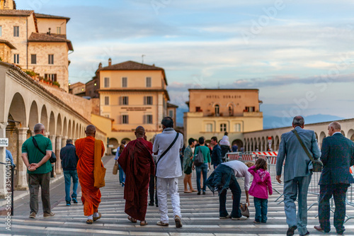 Persone di diversa nazionalità e fede religiosa camminano sulla piazza della Basilica di San Francesco ad Assisi, Umbria, Italia