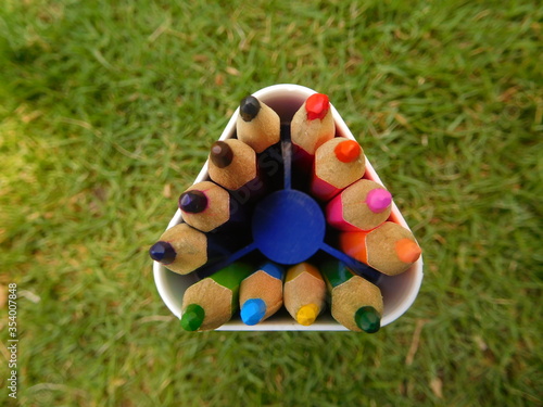 colored pencils in a basket. color pencils on grass in metallic container. Color pencil box, a closeup outdoor photo. Mini pencils of different colors for children for art and drawing work.