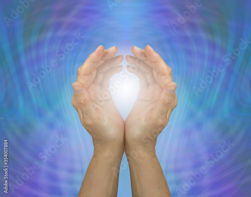 Pulsating Quantum Healing Energy  - cupped female hands embracing white healing light against a blue green energy matrix background 
 photo