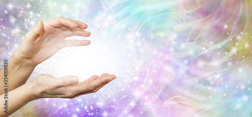 Feeling Healing Energy Between Hands - a pair of female hands with a white energy orb between on an ethereal pink and purple  energy field background 
 photo